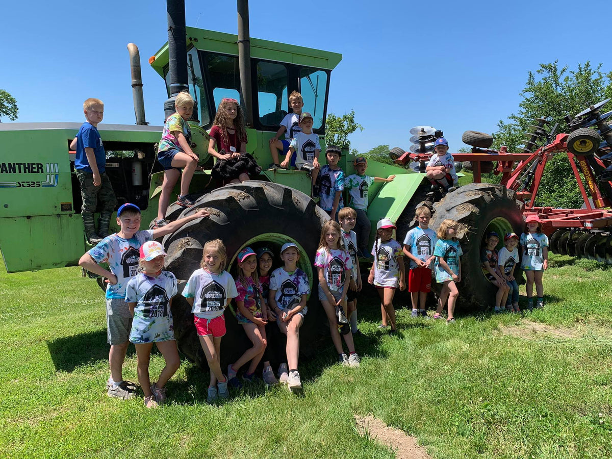 Children posing on a large tractor with a clear blue sky in the background
